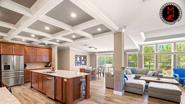A spacious kitchen with wooden cabinets, a central island, and a dining area with a table and chairs.