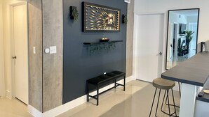 A modern kitchen with a bar area, a black bench, and a decorative wall piece.