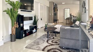 A modern living room with a flat-screen TV, a fireplace, a grey sofa, and a coffee table.