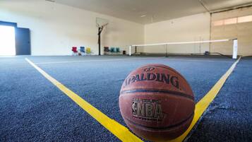 A basketball on an indoor court with a net and a basketball hoop.