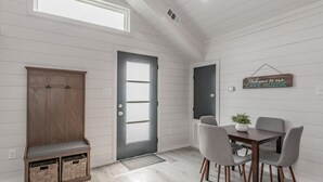 Un interno moderno con una panca di legno, un tavolo da pranzo con sedie e un cartello che dice 'Welcome to our LAKE HOUSE'.