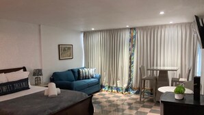 Ein Hotelzimmer mit einem Bett, einem blauen Sofa, einem Schreibtisch und einem karierten Boden.