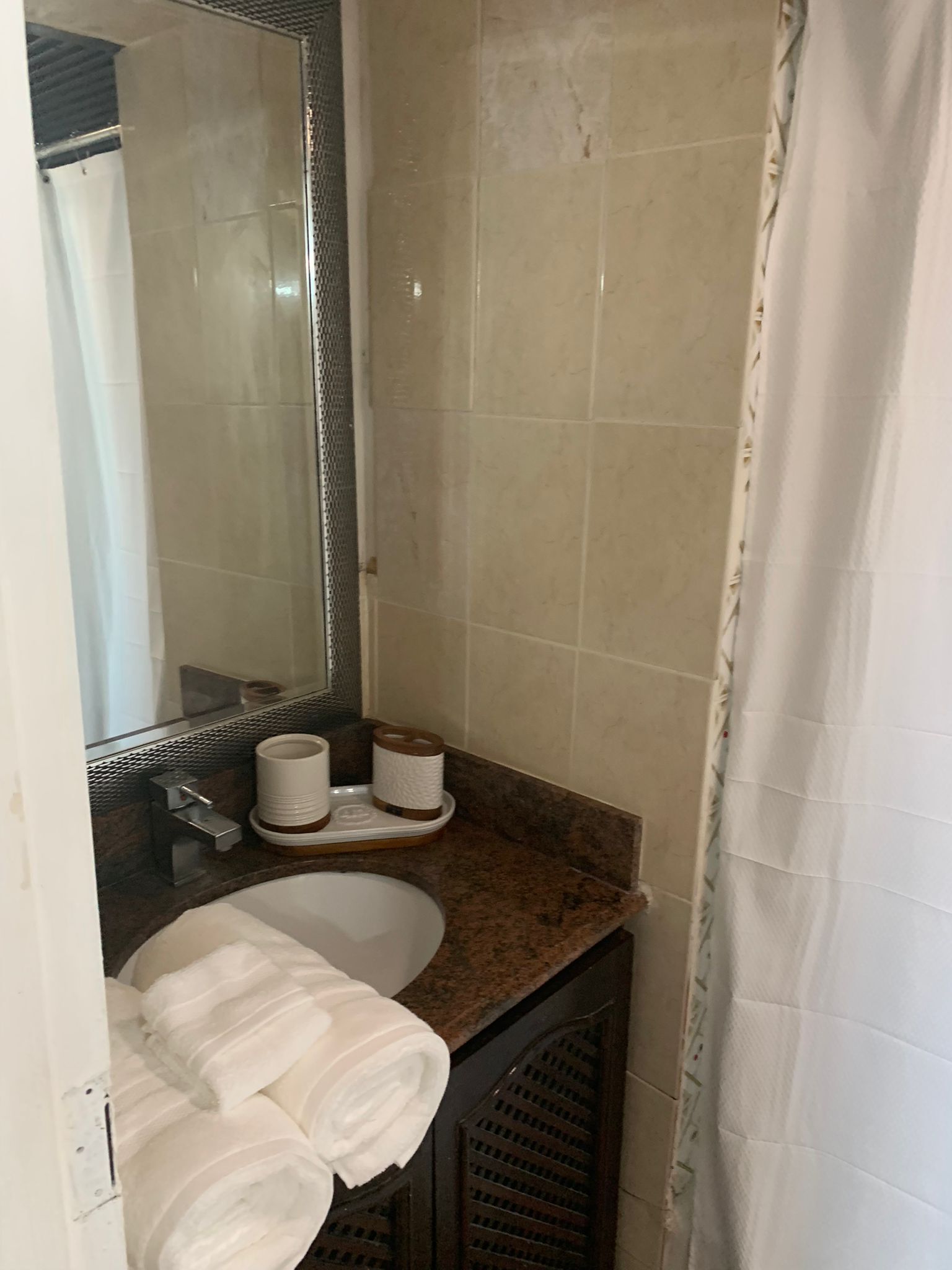 A bathroom with a sink, mirror, and towel rack.