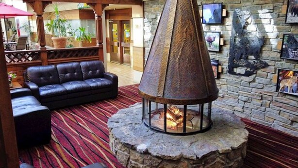 A lobby with a stone fireplace, leather seating, and a stone wall with artwork. - Christie Lodge Avon Vail for New Years (Avon)