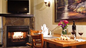 A cozy room with a fireplace, a dining table with a vase of flowers, and a painting on the wall. - Christie Lodge Avon Vail for New Years (Avon)