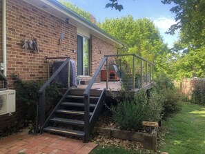 Une maison en briques dotée d’un espace extérieur couvert, d’un escalier menant à une terrasse et d’une pancarte de bienvenue.