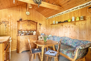 A wooden interior with a dining table, chairs, a sofa, and a cabinet.