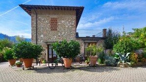 A stone building with a tiled roof, potted plants, and a bicycle parked outside. - Casa Teresa, Camaiore, Italy (Camaiore)