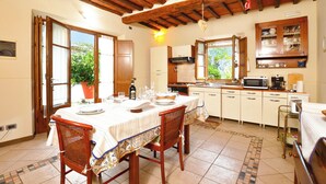 A kitchen with wooden beams, a dining table set for two, and a potted plant. - Casa Teresa, Camaiore, Italy (Camaiore)