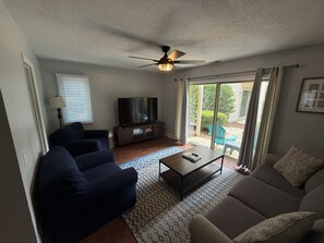 A living room with a ceiling fan, a television, two sofas, and a coffee table. - Dog Friendly Coligny Beach Townhouse - Minutes from the Beach! (Hilton Head Island)
