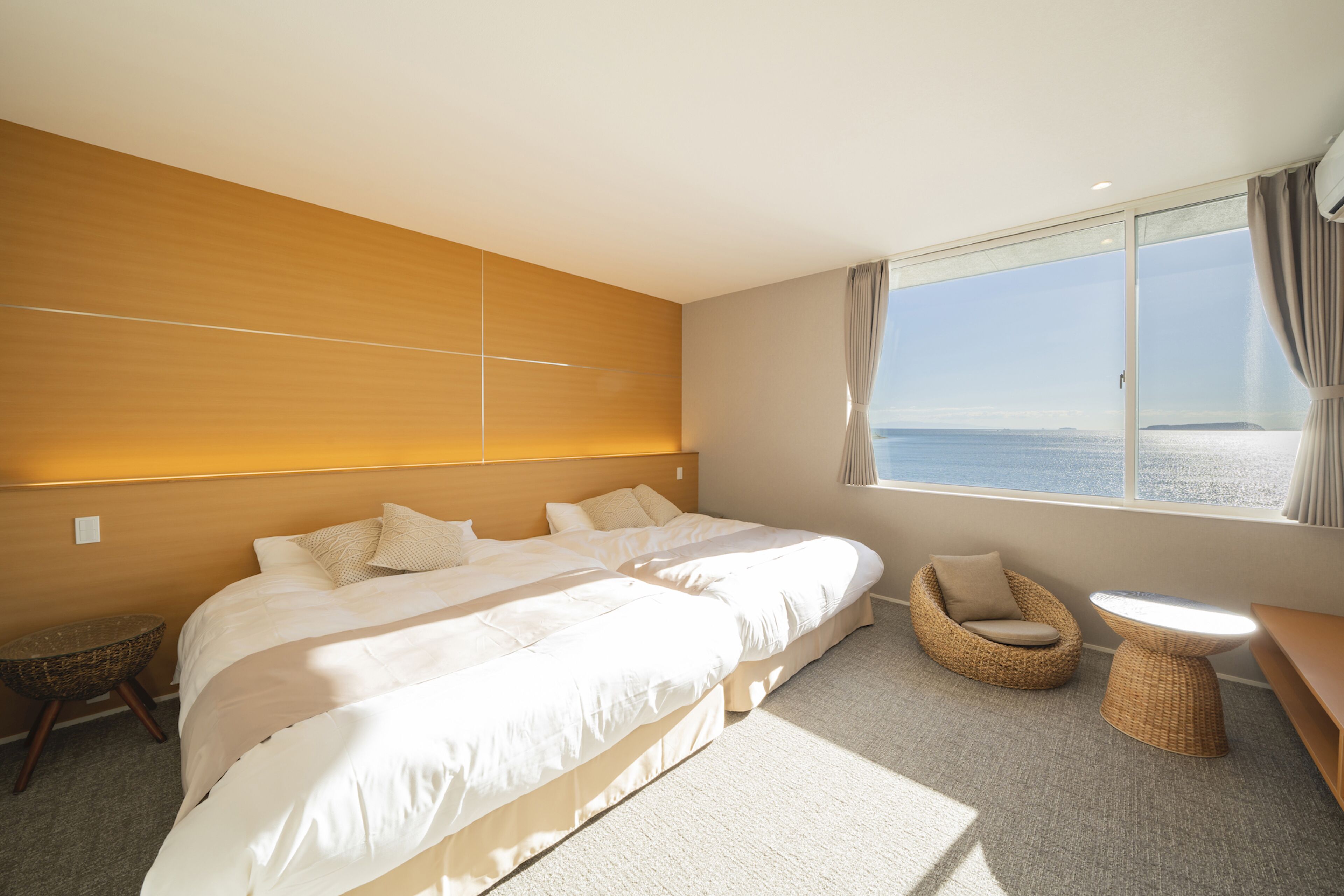 Une chambre d’hôtel avec un grand lit, un petit canapé, une table ronde et une vue sur la mer.