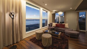 A modern living room with a large window overlooking the sea, a sofa set, and a floor lamp. - GLAMPREMIER Setouchi (Kanonji)