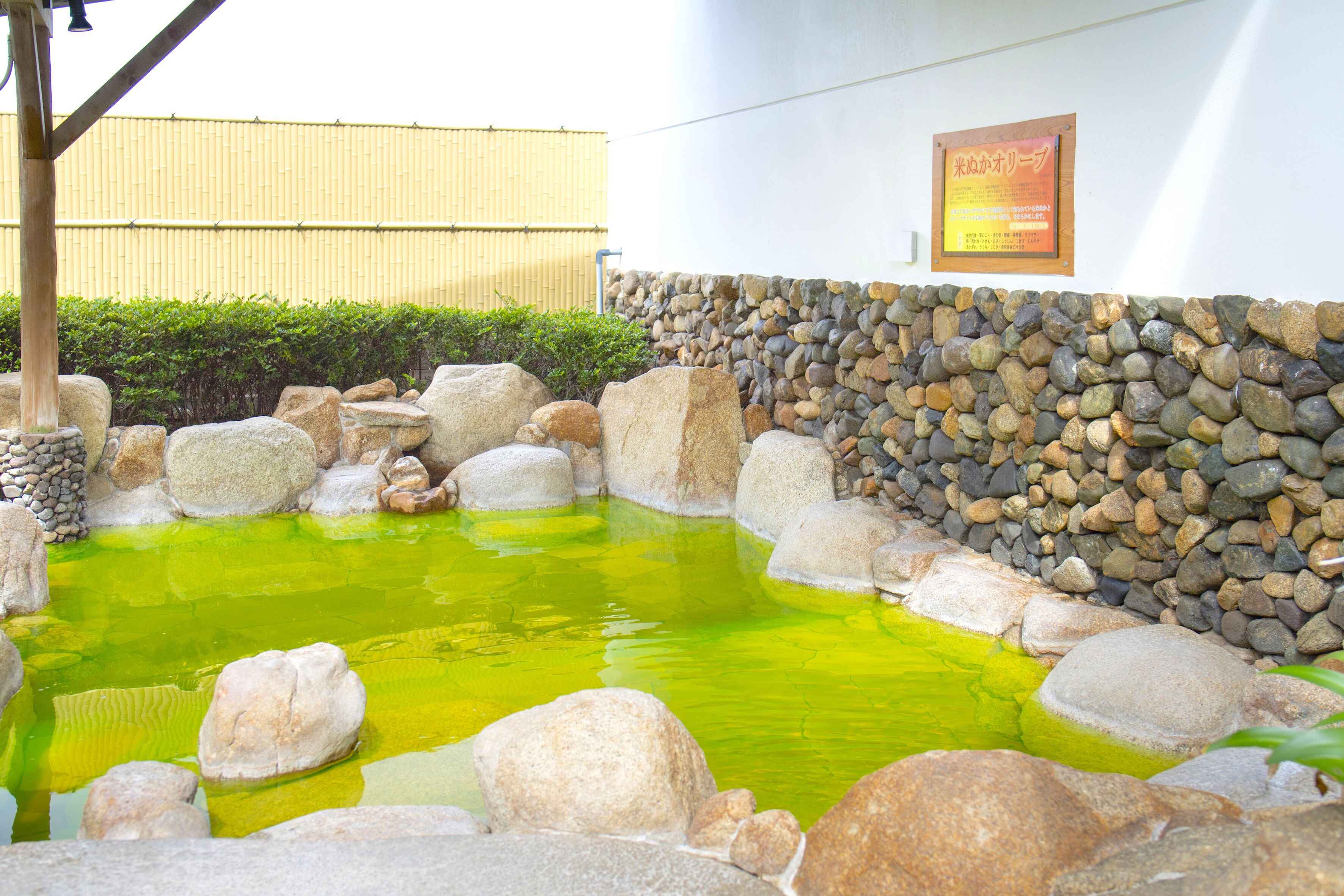 A traditional Japanese garden with a koi pond, stone walls, and a bamboo fence.