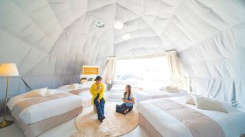 Um quarto amplo com tenda, duas camas, um tapete redondo e uma luminária.