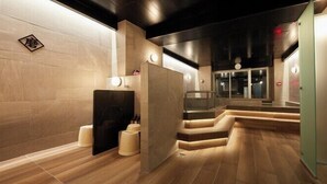 Un spa moderno con suelo de madera, una zona de estar central y un ascensor de vidrio.