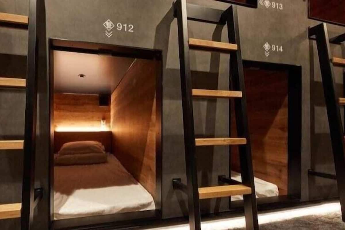 Een moderne hotelkamer met een stapelbed, houten latten en een klein nachtkastje.