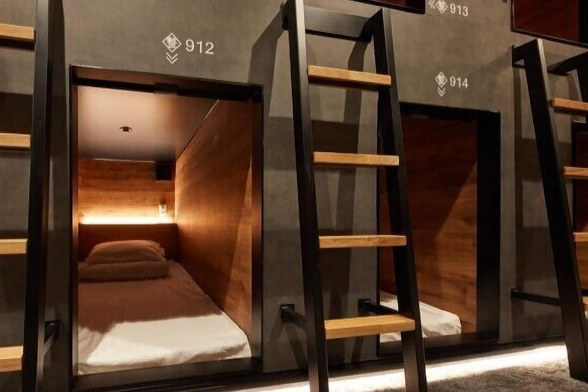 Een moderne hotelkamer met een minimalistisch design, met een bed met houten hoofdeinde en een klein nachtkastje.