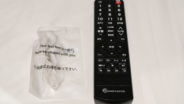 Un control remoto negro con texto en japonés y una caja de pañuelos blancos con texto en japonés.