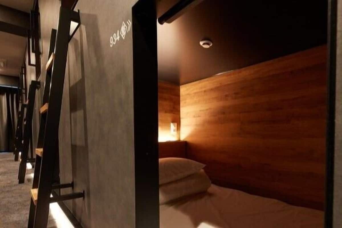Een hotelkamer met een houten hoofdbord, een bed met witte lakens en een nachtkastje.