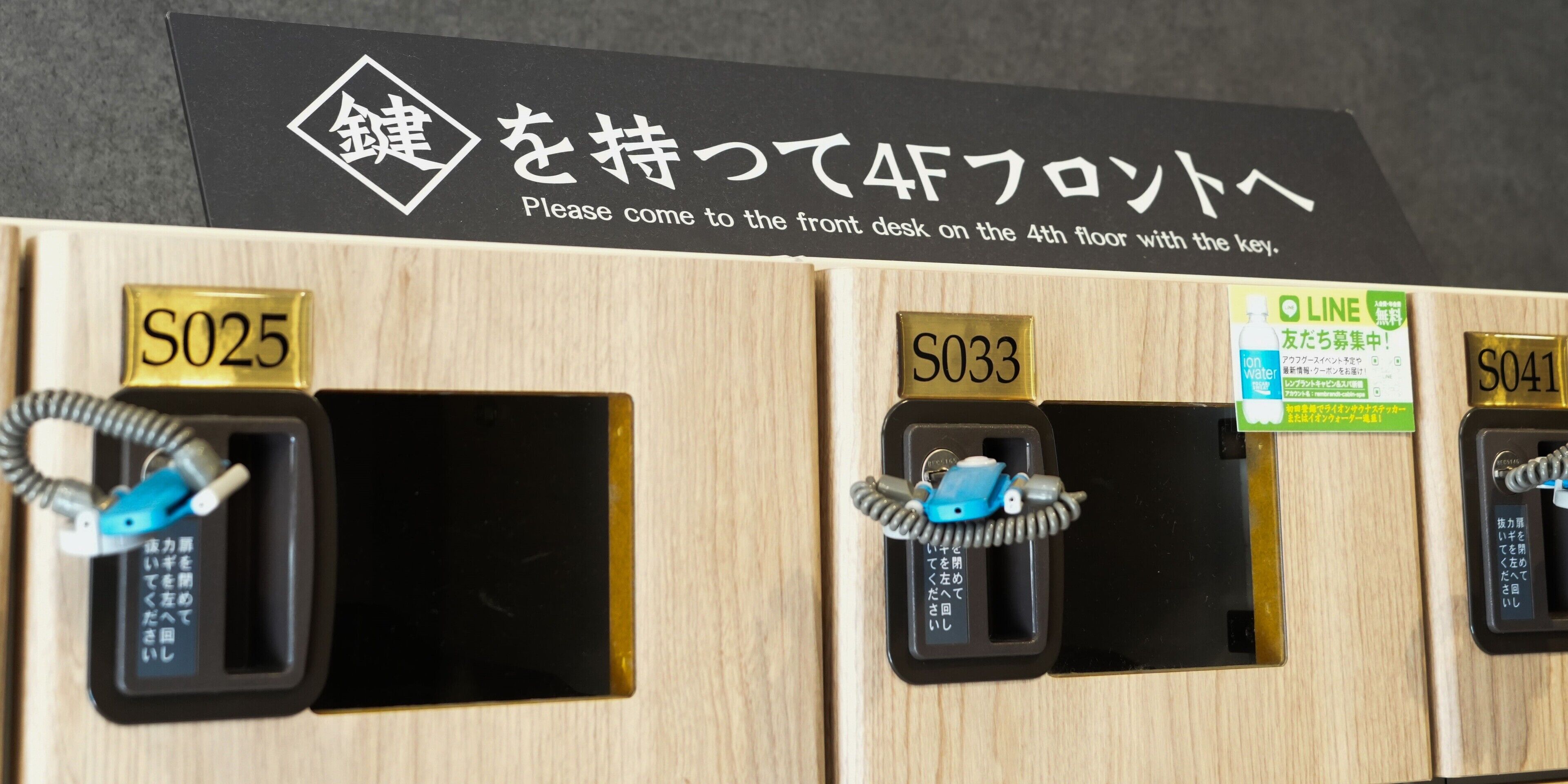 A hotel reception desk with signs indicating room numbers S025, S033, and S041.