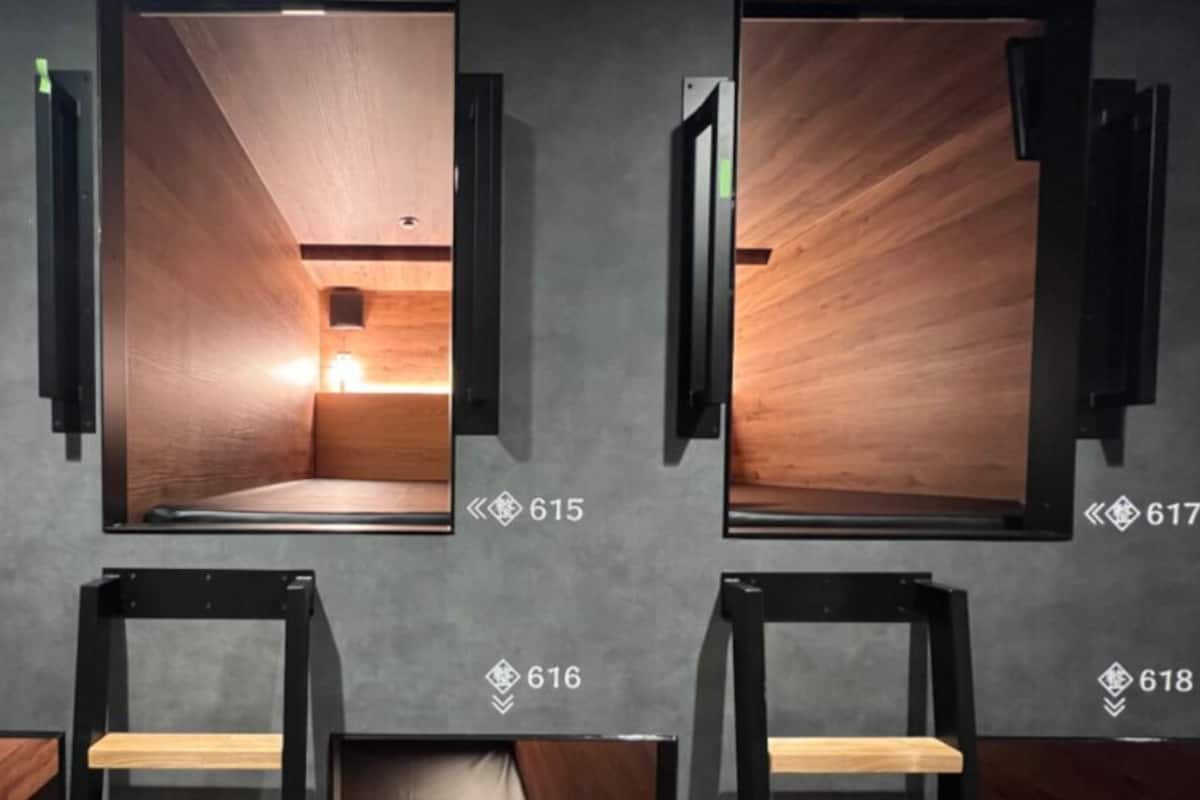 Een rij hotelkamers met houten lambrisering en genummerde deuren.