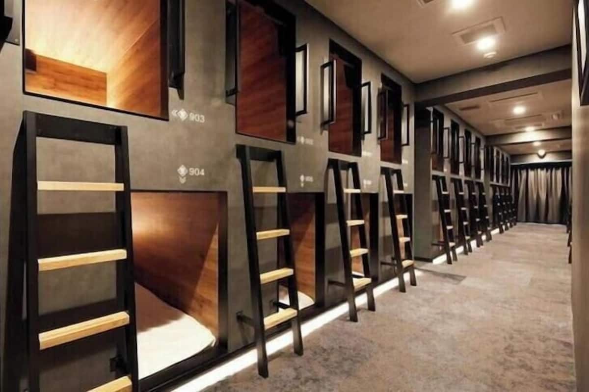 Een hotelgang met genummerde kamers, elk met een bed en nachtkastje.