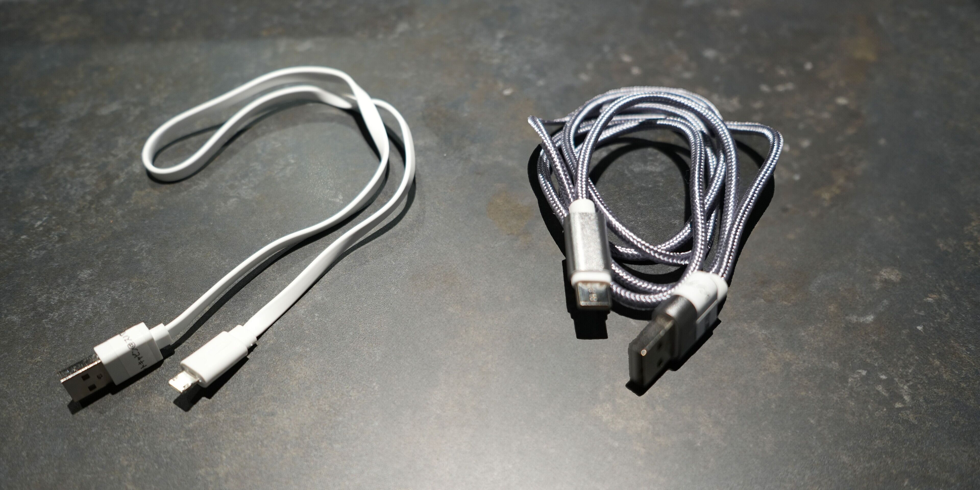 Kaksi USB-kaapelia tummalla alustalla.