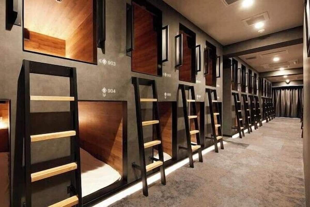 Een hotelgang met genummerde kamers, elk met een bed en nachtkastje.