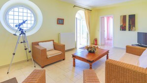 A spacious living room with a telescope, wicker furniture, a fireplace, and artwork on the walls. - House On The Rocks in Nisaki (Corfu)