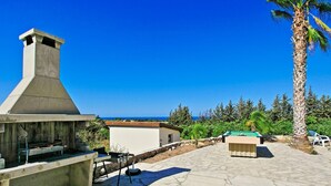 Eine Terrasse im Freien mit Grillplatz, Billardtisch und Meerblick.