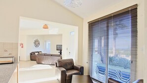 Ein modernes Wohnzimmer mit Ledersofas, einem Couchtisch und einem großen Fenster mit Jalousien.