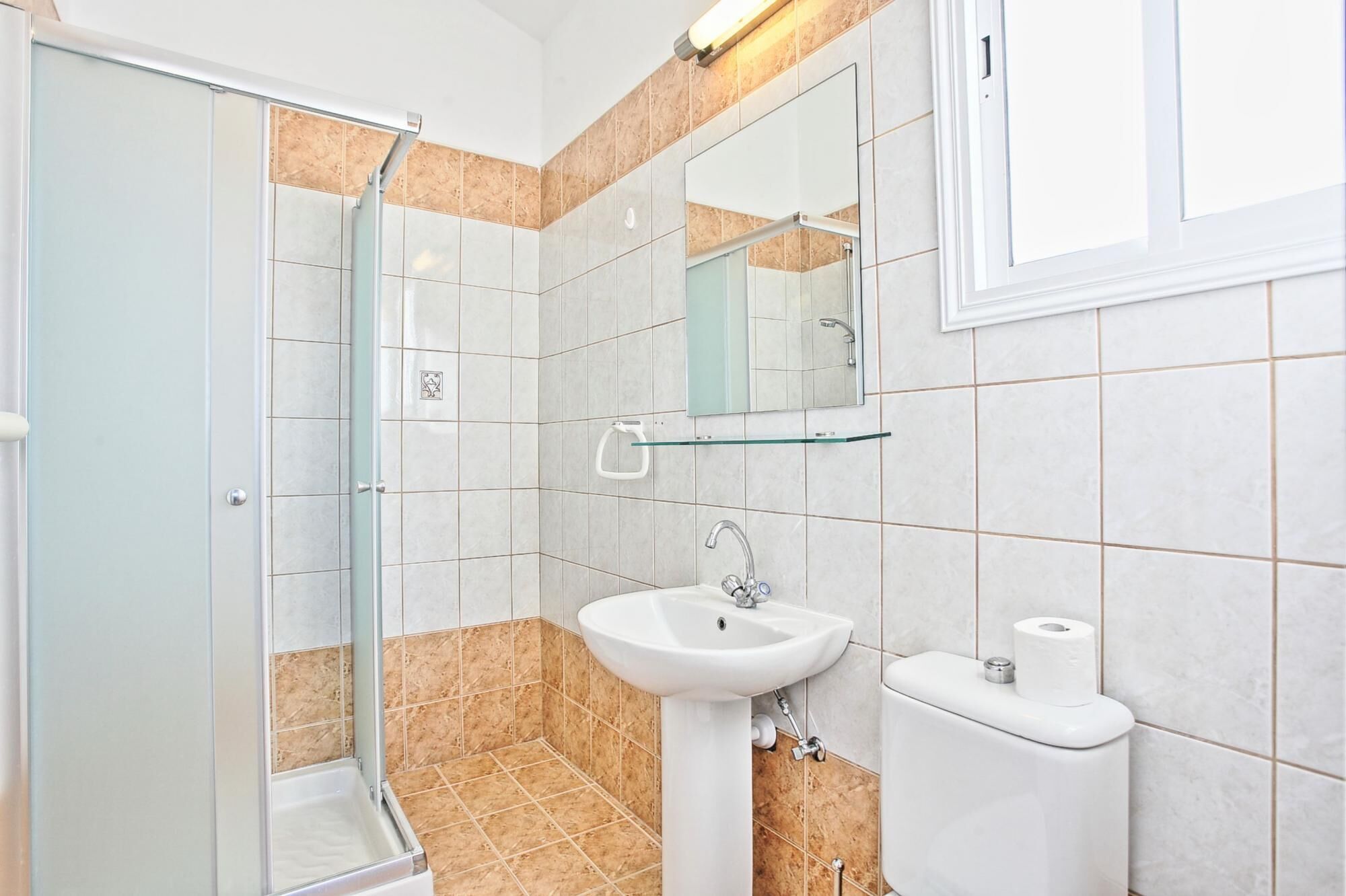 Un baño con cabina de ducha de vidrio, un lavamanos blanco y un inodoro.