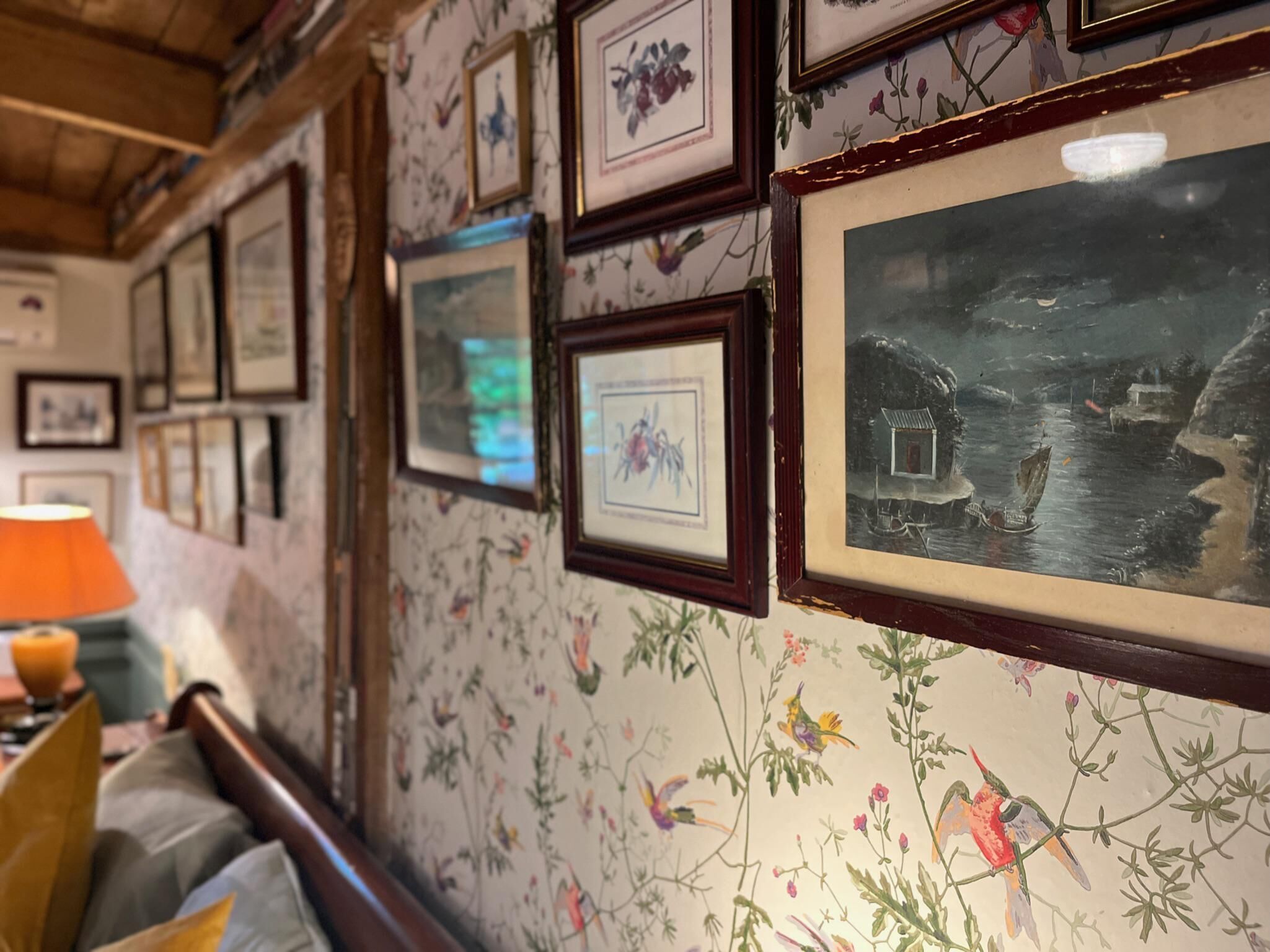A wall with framed pictures and a floral wallpaper pattern.