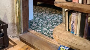 A cozy room with a wooden bookshelf filled with books, a wooden desk, and a patterned carpet.