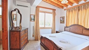 A bedroom with a wooden bed, a dresser, a mirror, and a window with curtains.