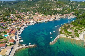 An aerial view of a coastal town with a marina, houses, and a rocky shoreline. - Villa Thea Antonis in Gaios (Paxos)