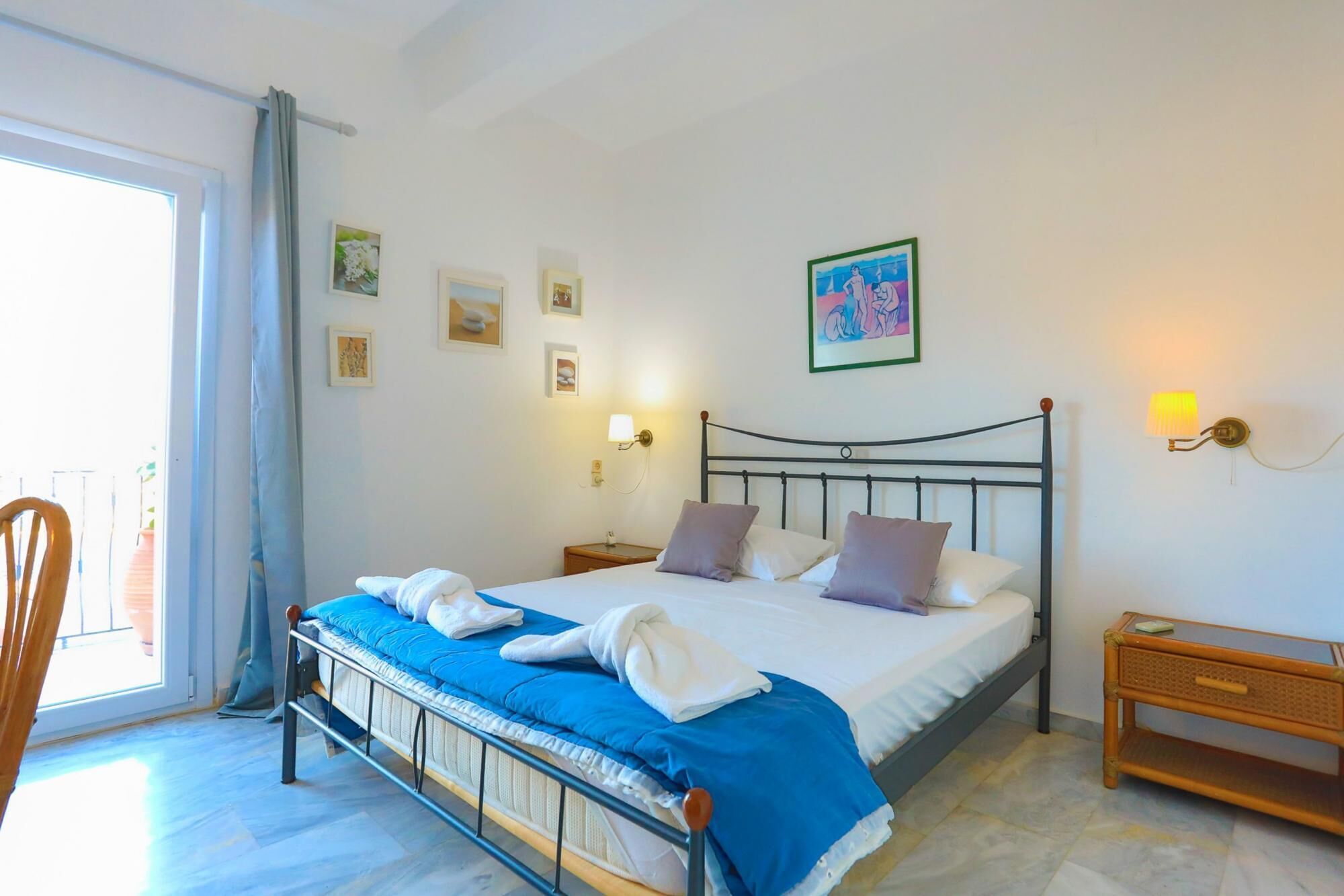 A bedroom with a bed, pillows, a nightstand, a lamp, and a picture on the wall.