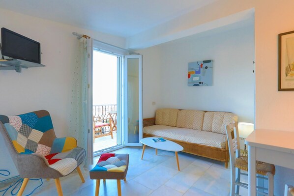A living room with a sofa, a chair, a small table, and a TV mounted on the wall. - Sterna Suite in Gaios (Paxos)