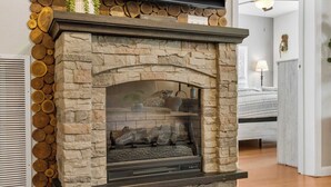 A stone fireplace with a glass door, surrounded by a stack of logs. - Valley View Treehouse - Holiday Hills Branson Golf Resort Outdoor Pools (Branson)