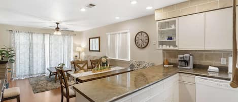 A modern kitchen with white cabinets, a built-in dishwasher, and a countertop with a coffee maker.