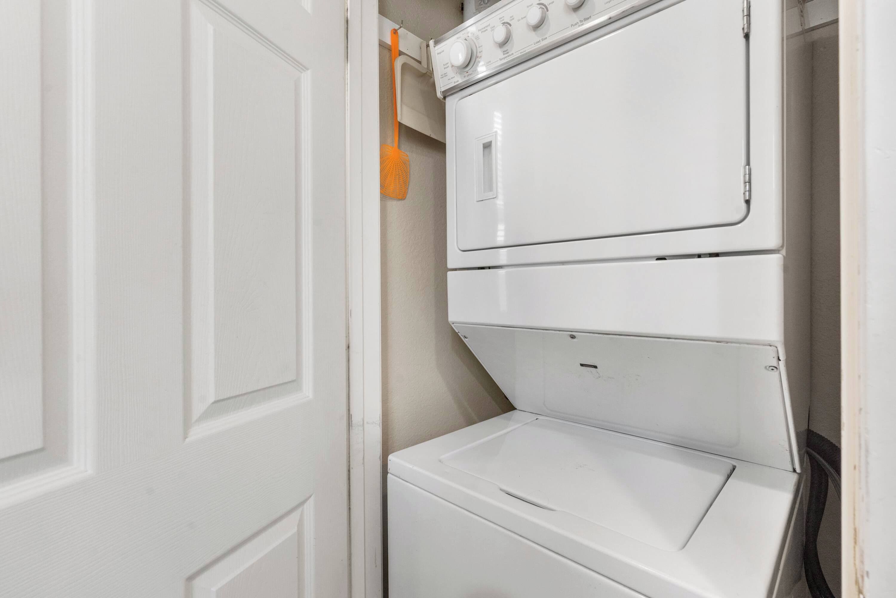 A white wall-mounted washer and dryer unit with a control panel and a hanging orange clothespin.