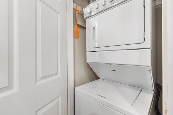 A white wall-mounted washer and dryer unit with a control panel and a hanging orange clothespin.