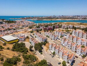 A coastal residential area with modern apartment buildings, a marina with boats, and a clear view of the sea. - Casa Almar by Portucasa (Lagoa)