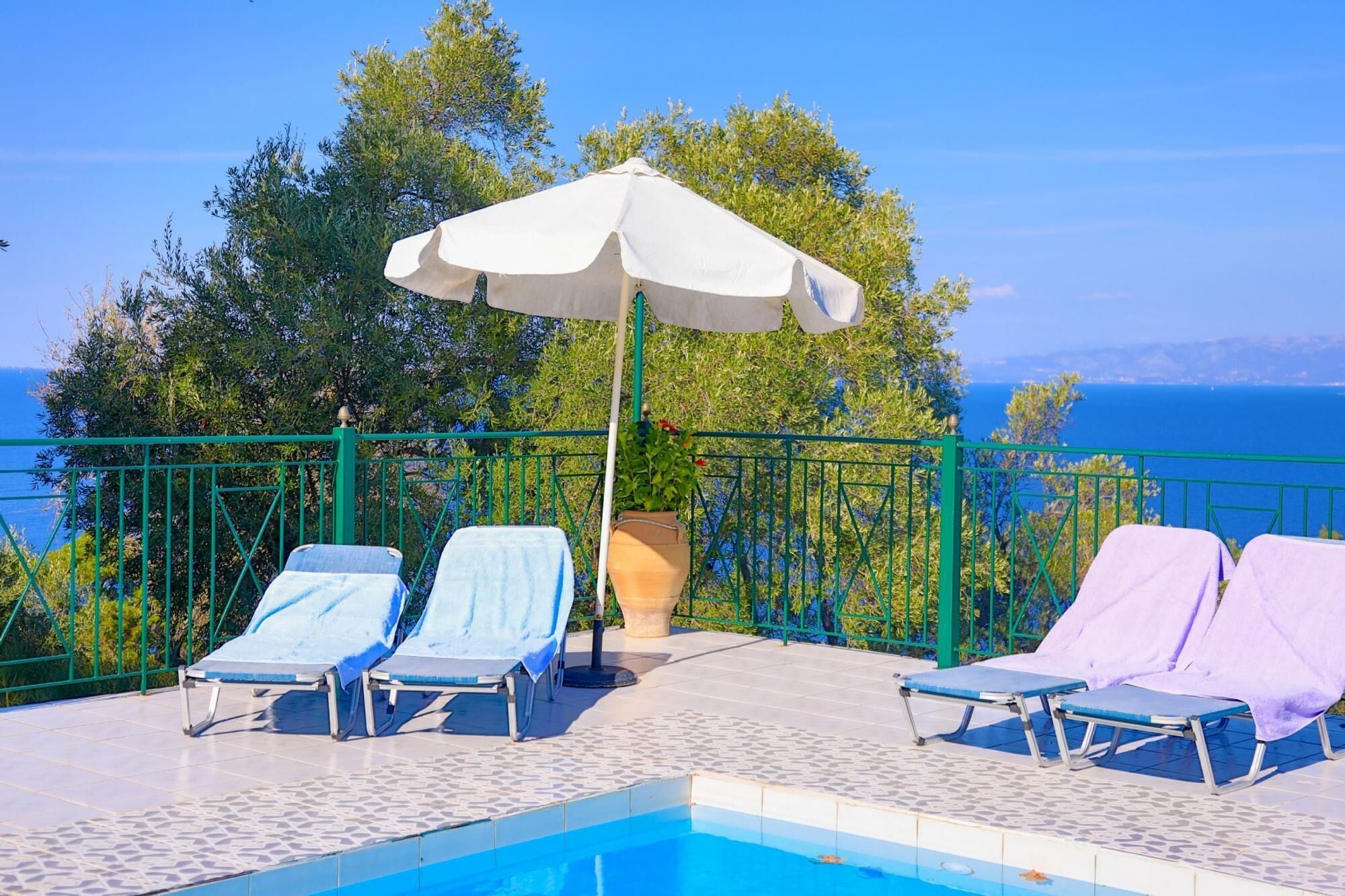 Ein Poolbereich mit Liegestühlen und einem großen Sonnenschirm.