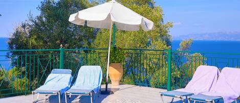Ein Poolbereich mit Liegestühlen und einem großen Sonnenschirm.