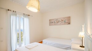 A bedroom with two beds, a painting on the wall, and a window with curtains. - Antigoni Villa Dio in Longos (Paxos)