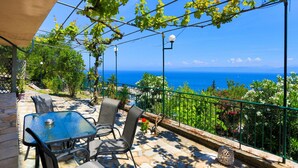 A terrace with a table and chairs, a view of the sea, and a pergola with vines. - Antigoni Villa Dio in Longos (Paxos)
