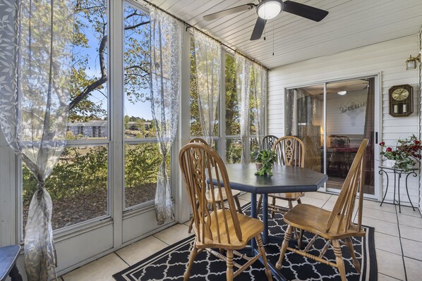 Enjoy a peaceful retreat in this serene sunroom with a large door leading to a residential view, a round table, and comfortable seating for four.