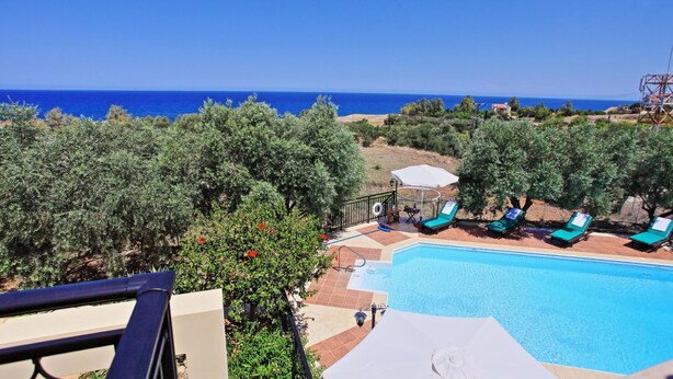 Zona de piscina con sillones reclinables y vista al mar.