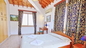 Un dormitorio con una cama de madera, un escritorio con lámpara y cortinas estampadas.